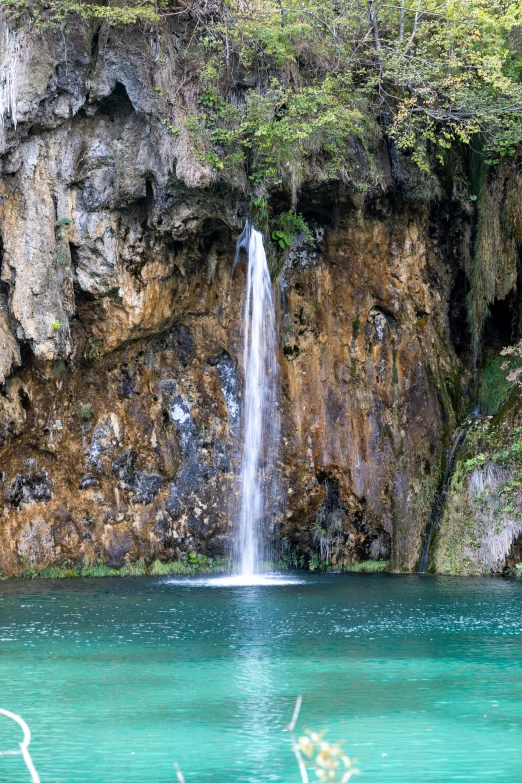 the waterfall has a small body of water in front