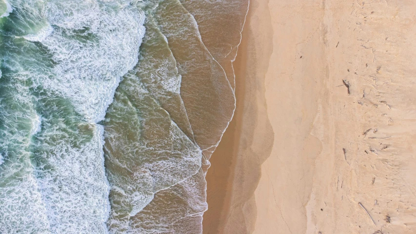 an aerial view of a beach with a surfboard on the sand