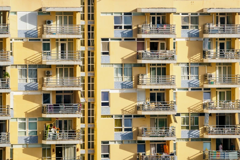 a tall yellow apartment building has balconies and windows