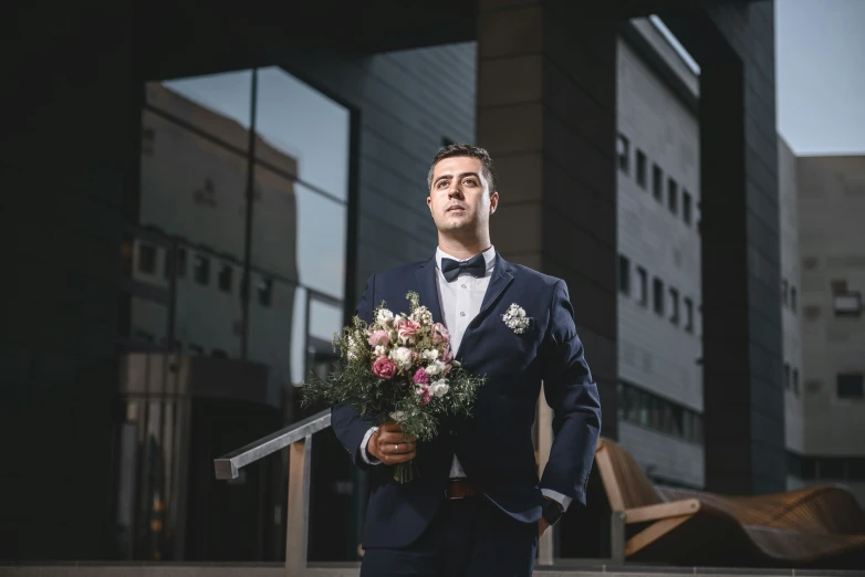 a man in a blue jacket and white shirt holding flowers