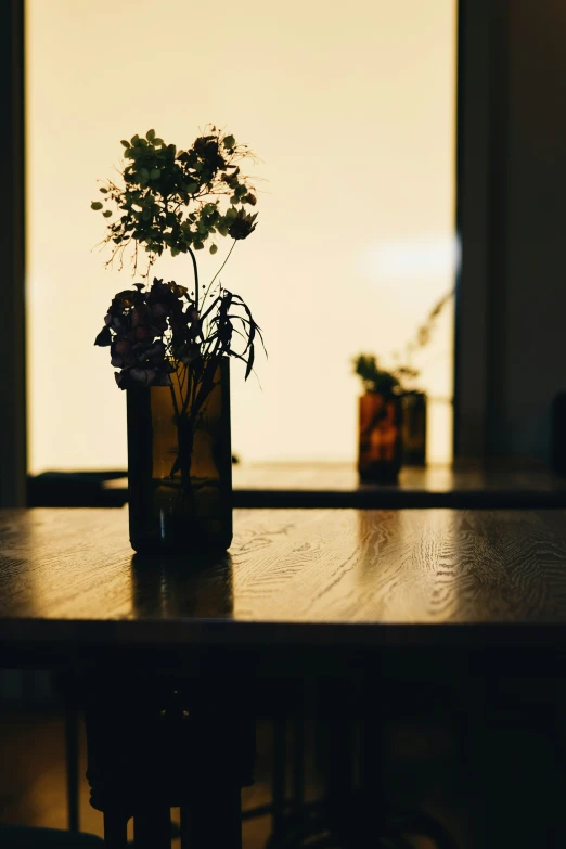 a small vase of flowers is in front of a window