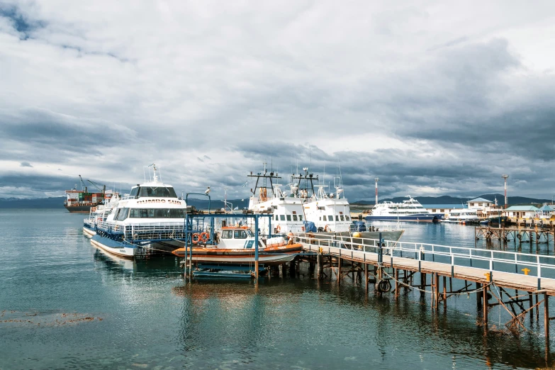 several boats parked on a dock surrounded by dark clouds