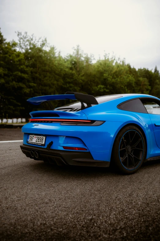 a blue sports car on the road with trees in background