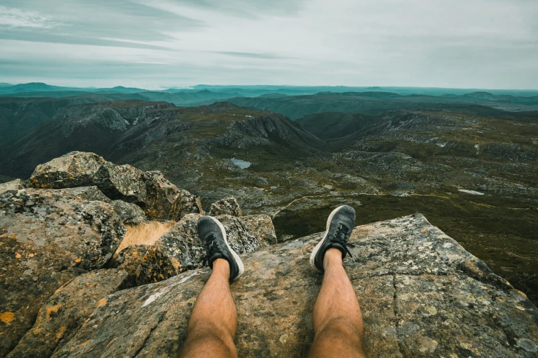 man sitting on top of rock overlooking mountain valley