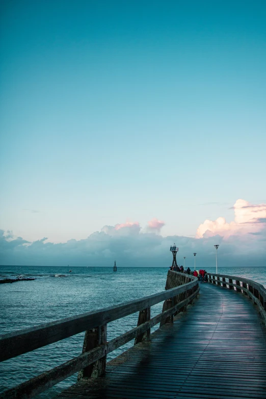 people walk along a long dock by the water