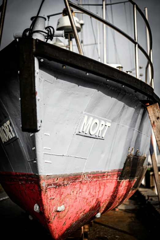 a grey and red boat docked in the water