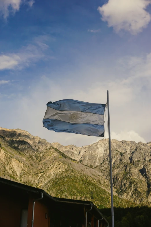 a flag flying outside a building by a mountain