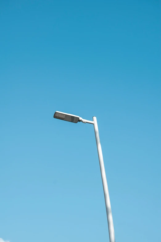 two street lamps are seen against the blue sky