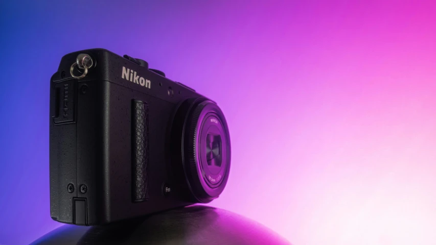 a camera sitting on top of an object in front of pink and purple lights