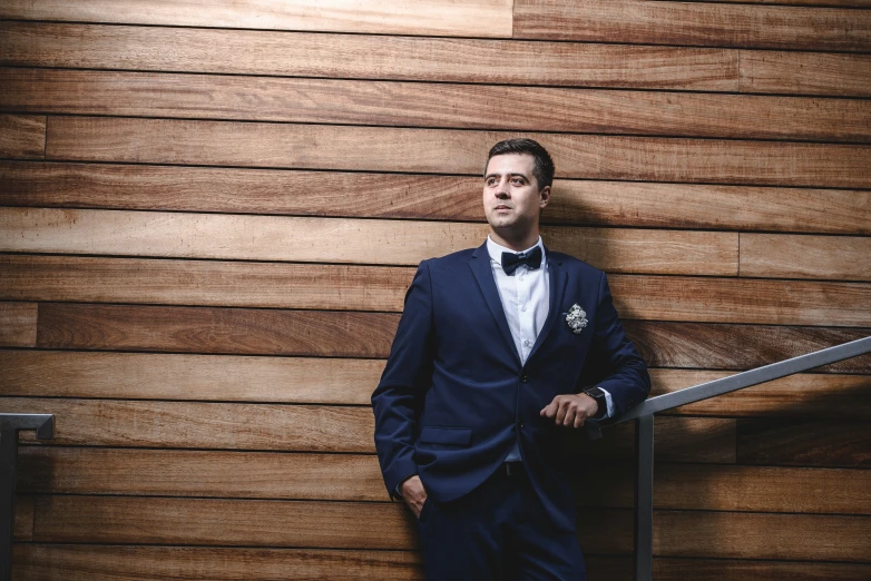 man in blue suit standing with hands on railing