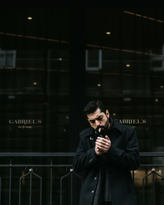 a man standing outside of a building holding a cigarette
