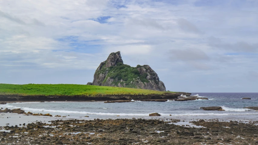 the rocks are on the beach and there is a small hill