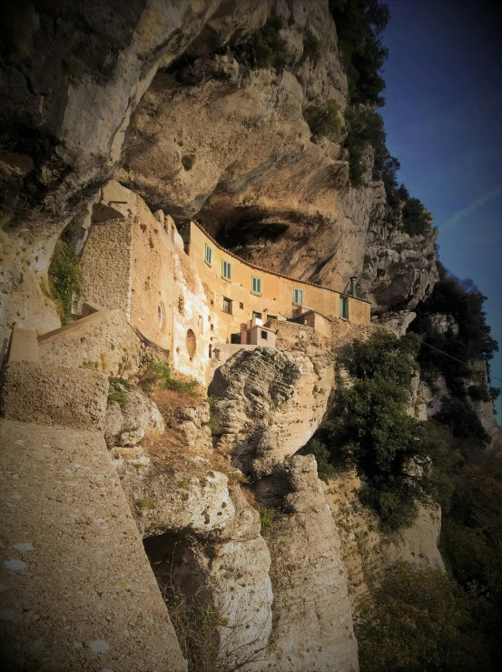 a small building sits atop the rocky hillside