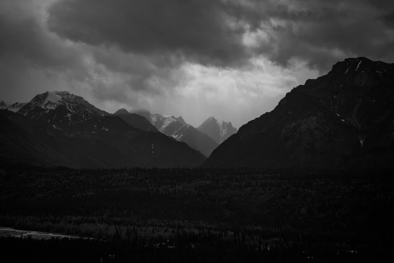 a black and white po of mountains under dark clouds