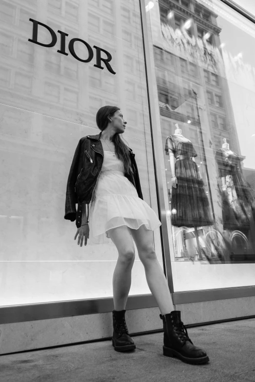 a young woman is walking by a giant dior window