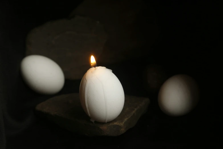 small lit candle sitting on top of a stone block