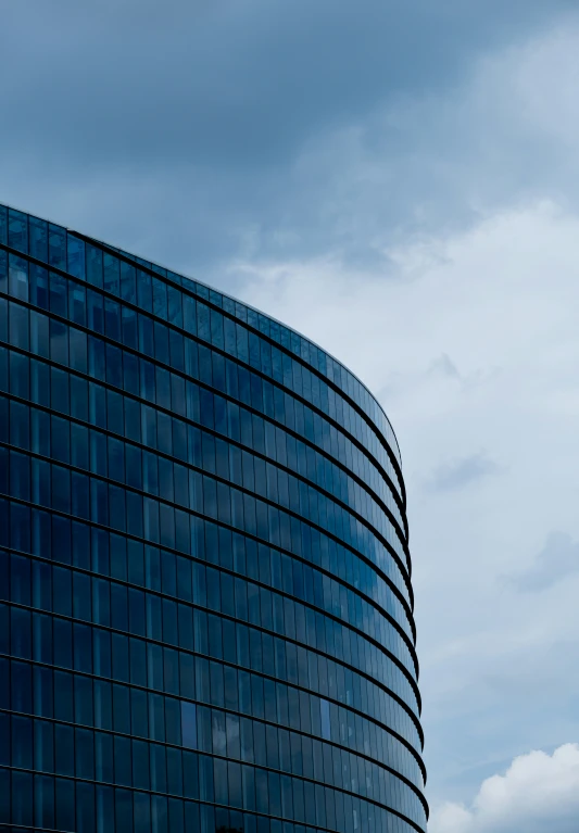 the top of a very tall glass building under cloudy skies