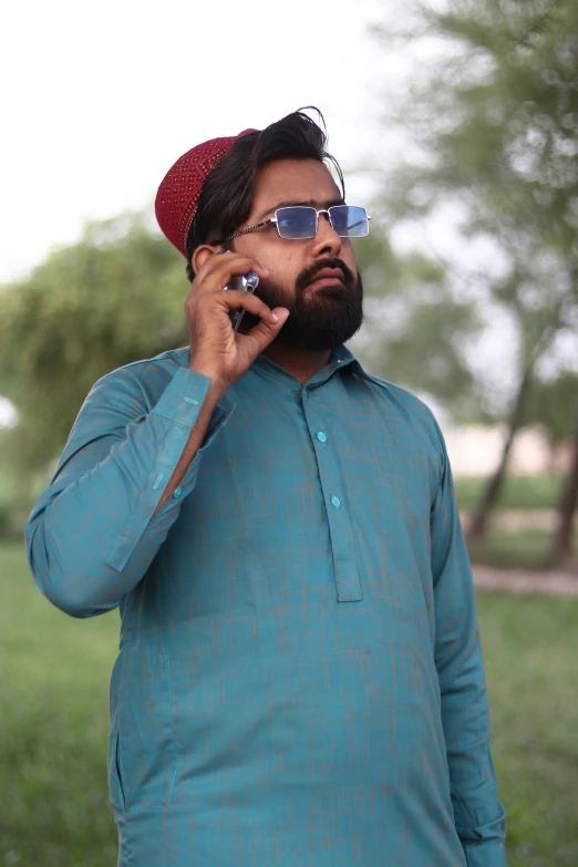 man in sunglasses and green shirt talking on a cell phone