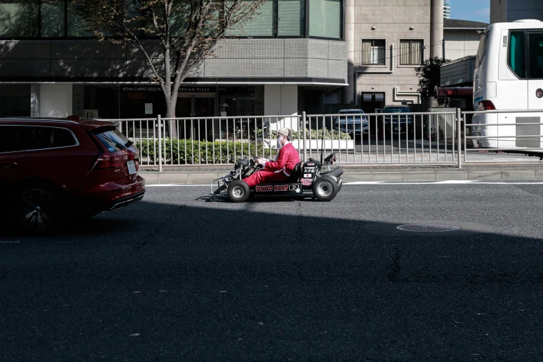 a person in pink clothes on a small motorbike in the street near some buildings