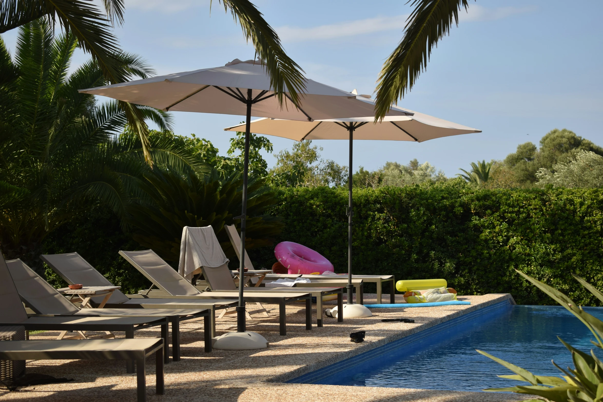 several lawn chairs and umbrellas next to a pool