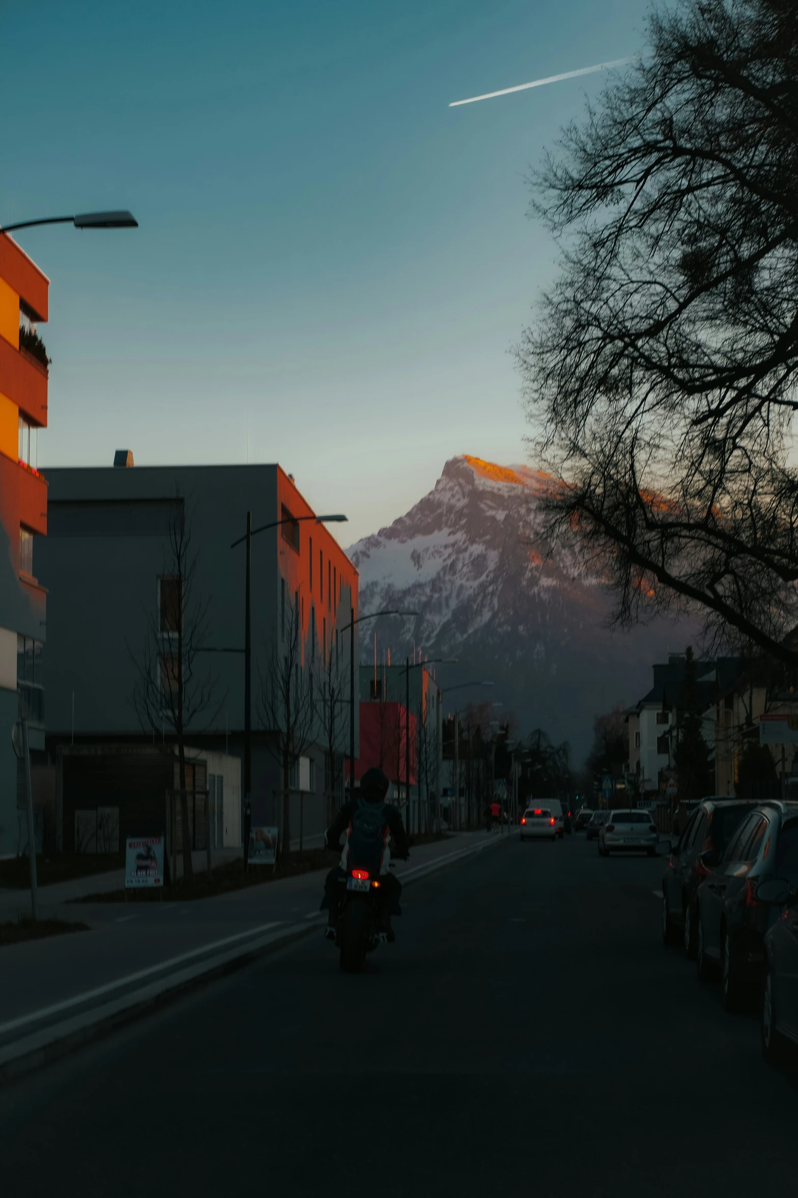 a person on a motorcycle near buildings with a mountain in the background