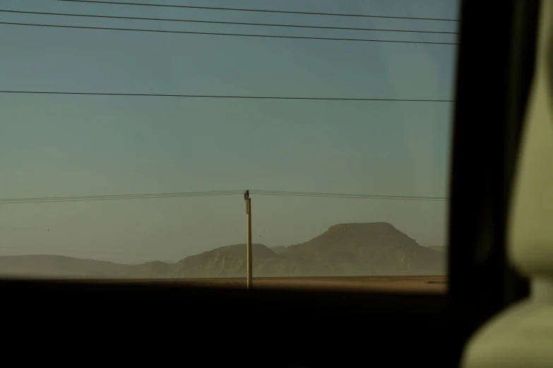 a train window showing a mountain and a sky