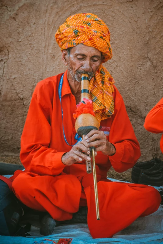 an older man with bright clothes plays flute