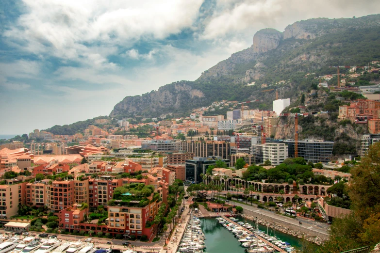 a city skyline overlooks a marina below a rocky mountain