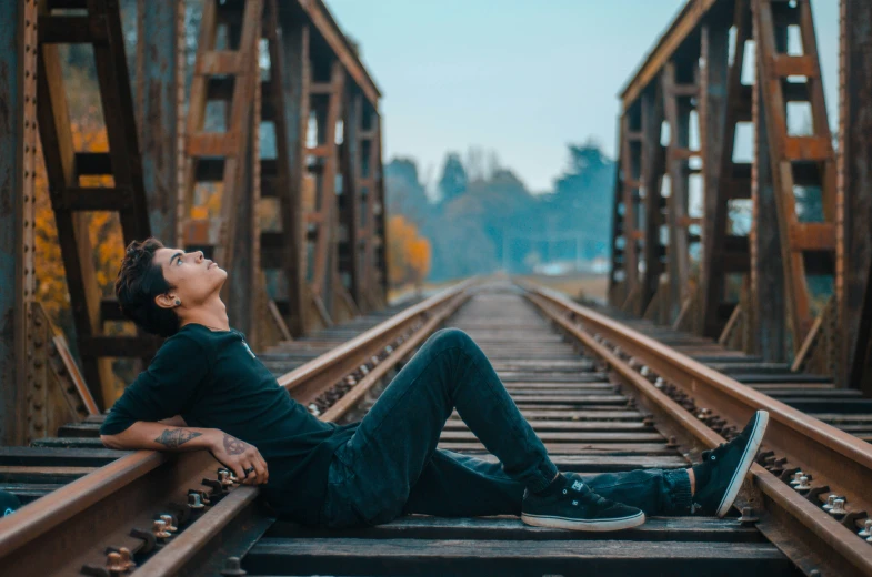 a person laying down on the tracks with a phone