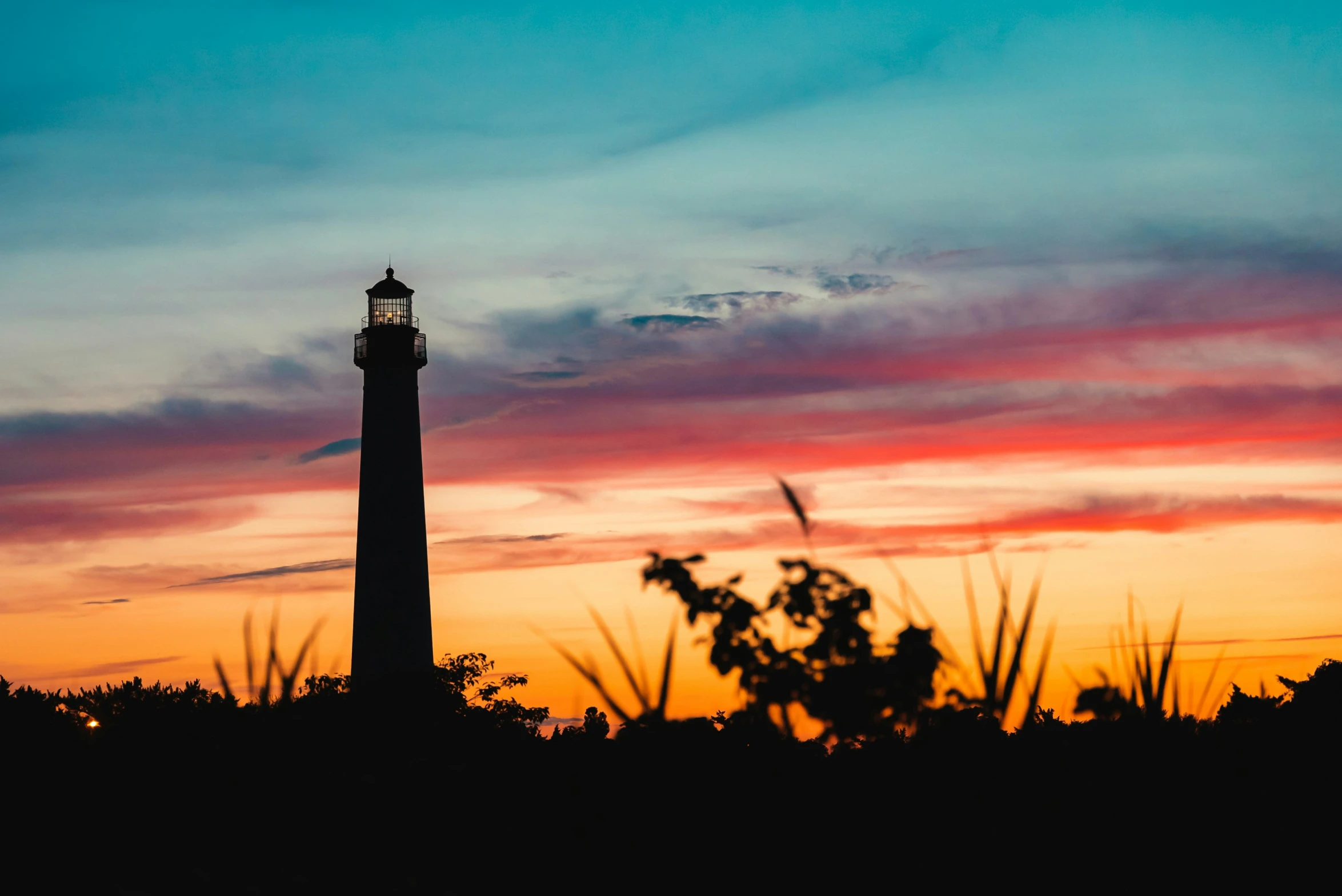 the silhouette of a lighthouse against a dusk sky