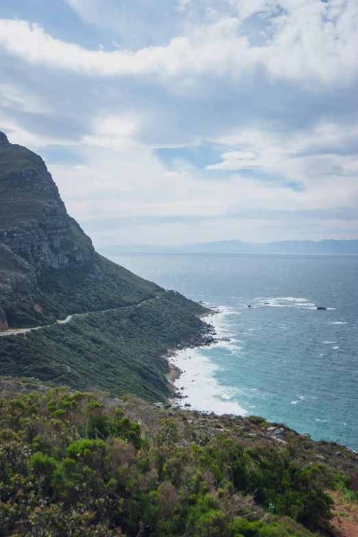 a large hill next to the ocean with a sky background