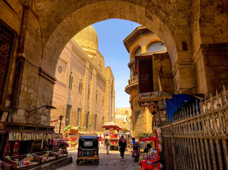 an archway has people and cars in the street