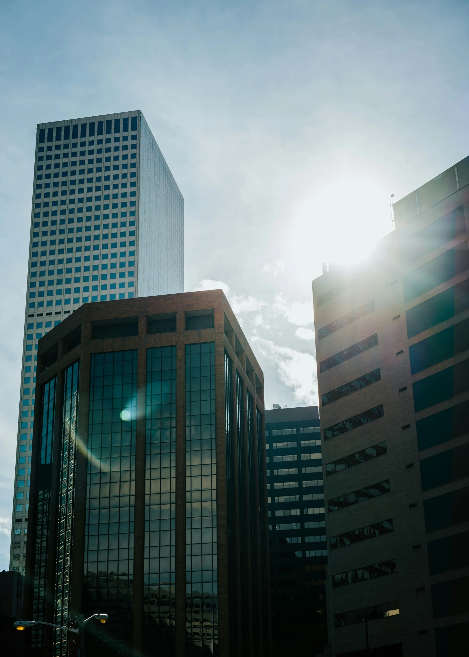 a couple of tall buildings with the sun shining in the background