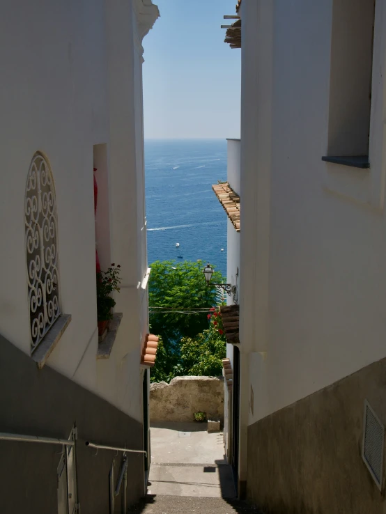 an alley between buildings with blue ocean in the background