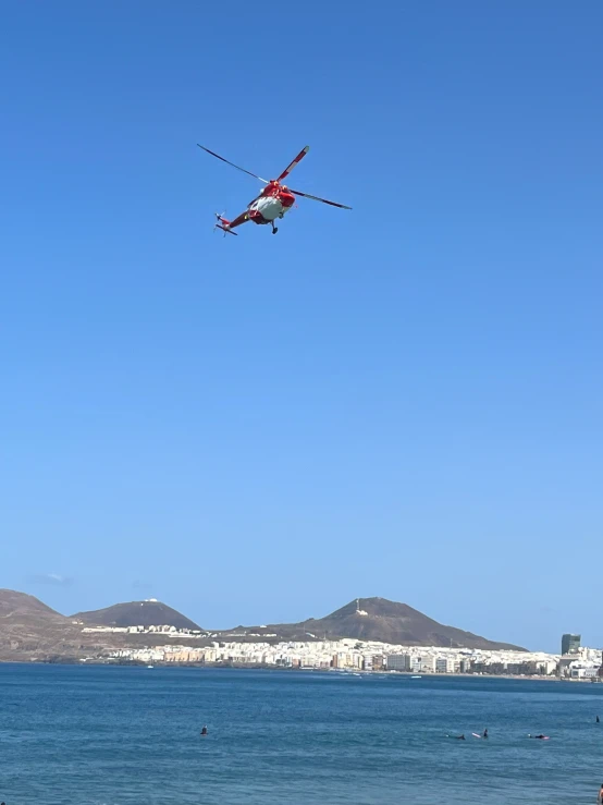 a plane flying low above the ocean with people on a beach