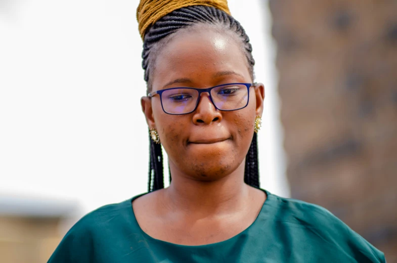 a woman wearing blue and pink glasses is standing in front of a brick wall