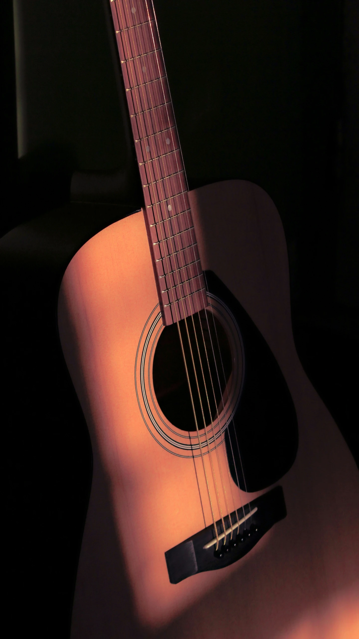 an acoustic guitar is laying on its side, a shadow cast by it
