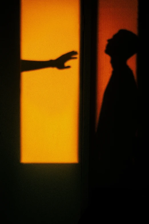 a shadow of a man pointing at soing on a wall