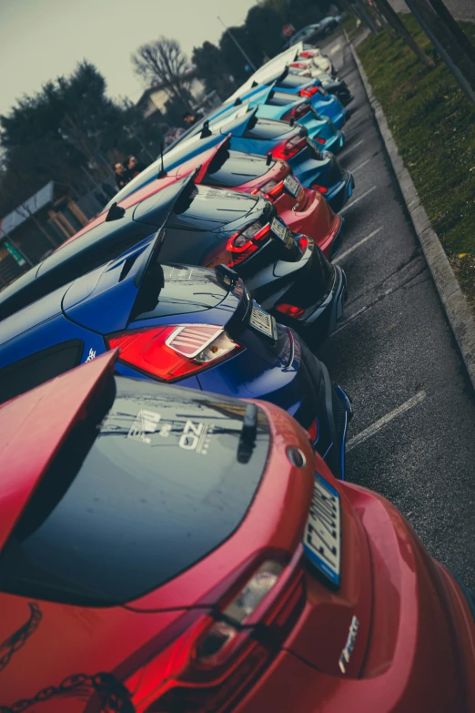 rows of sports cars in parking lot next to grassy area