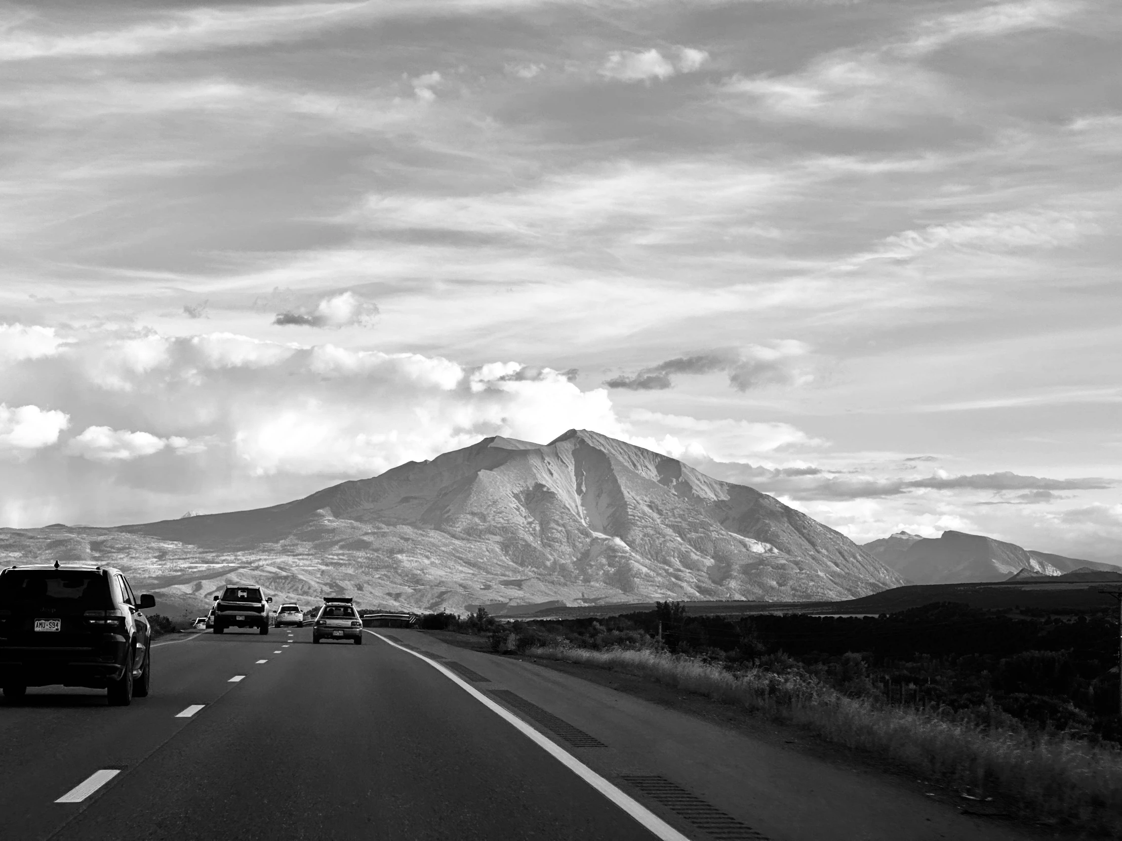 several vehicles driving down the road in black and white