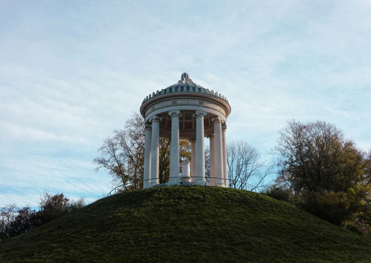 a white tower stands on top of a lush green hill