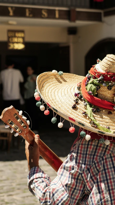 man with straw hat and guitar outside building