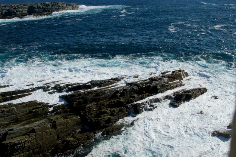 an ocean with rocks and the water crashing onto the shore