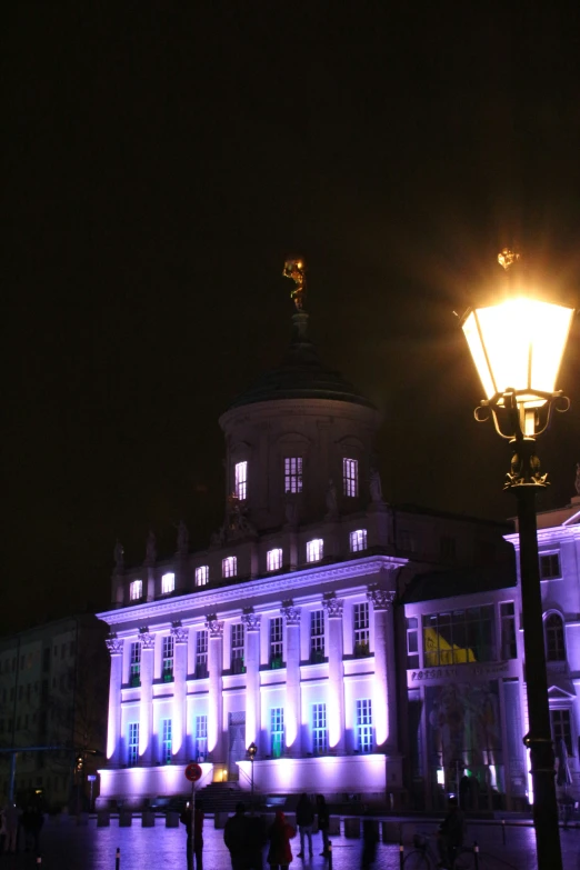 a building in the dark with lights on and people around it