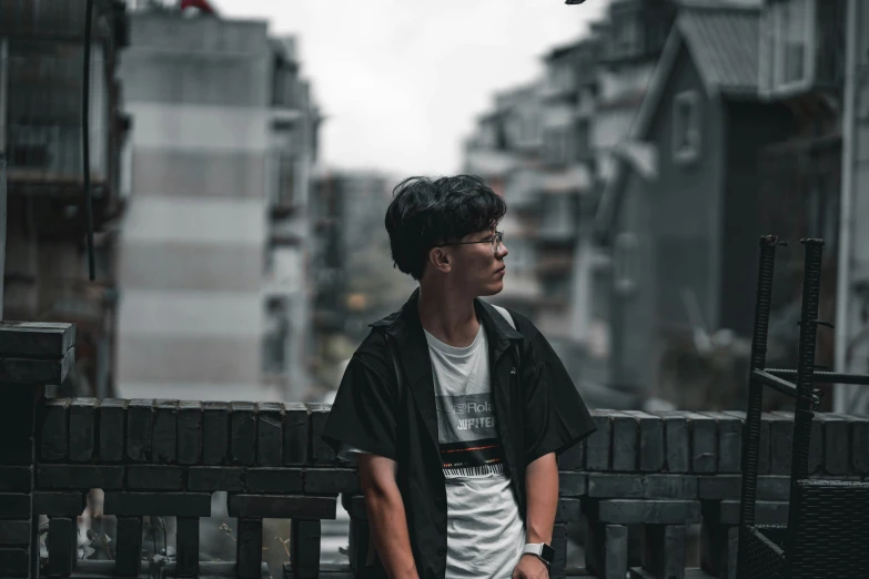 a young man standing against a brick wall