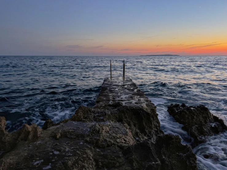 two fishing rods stuck in a rock along the edge of a pier