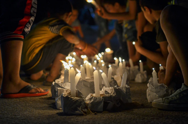 many candles are lit while people stand around