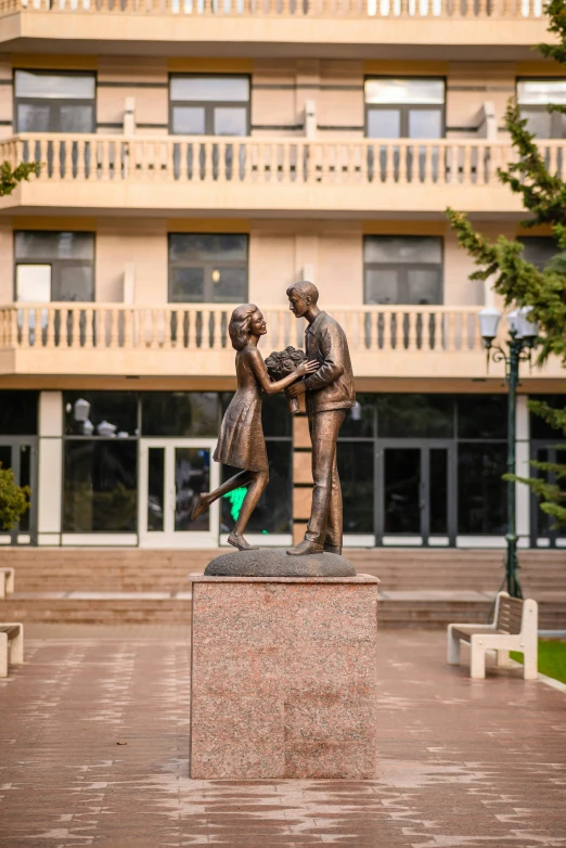 a bronze statue of two people on the corner of a courtyard