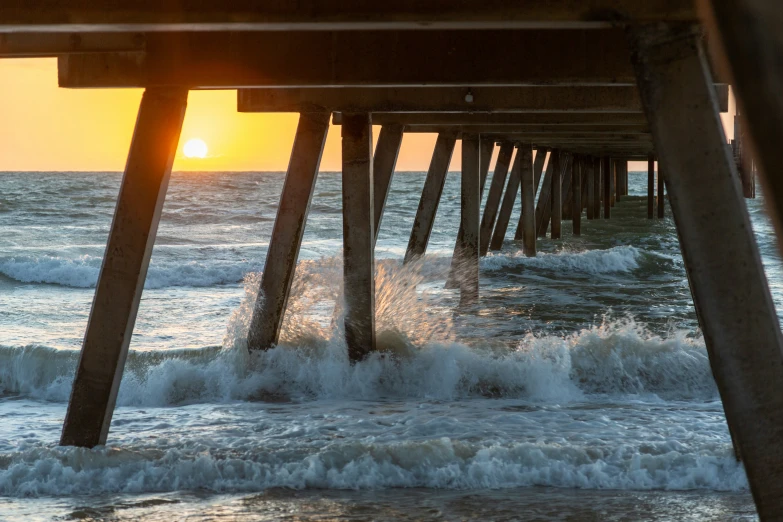 a man is standing at the end of a wooden pier on an ocean