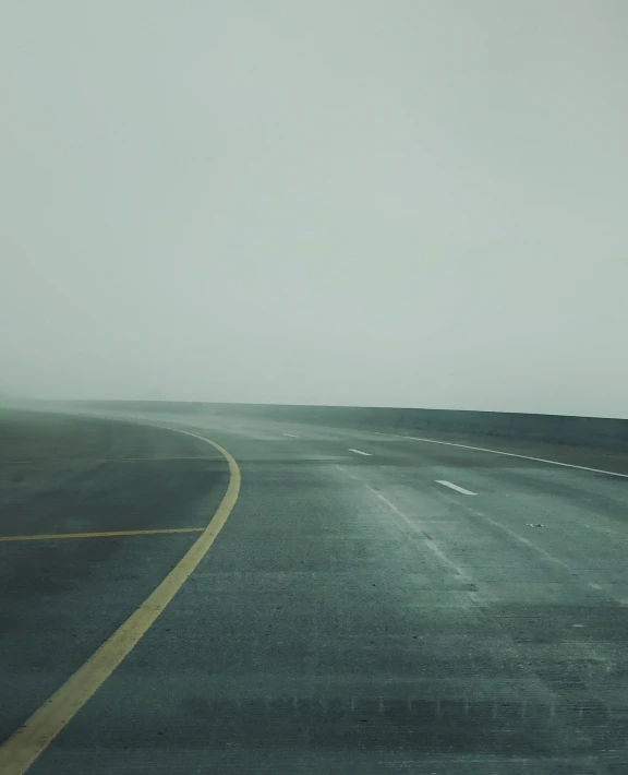 a curved highway in an empty valley with fog